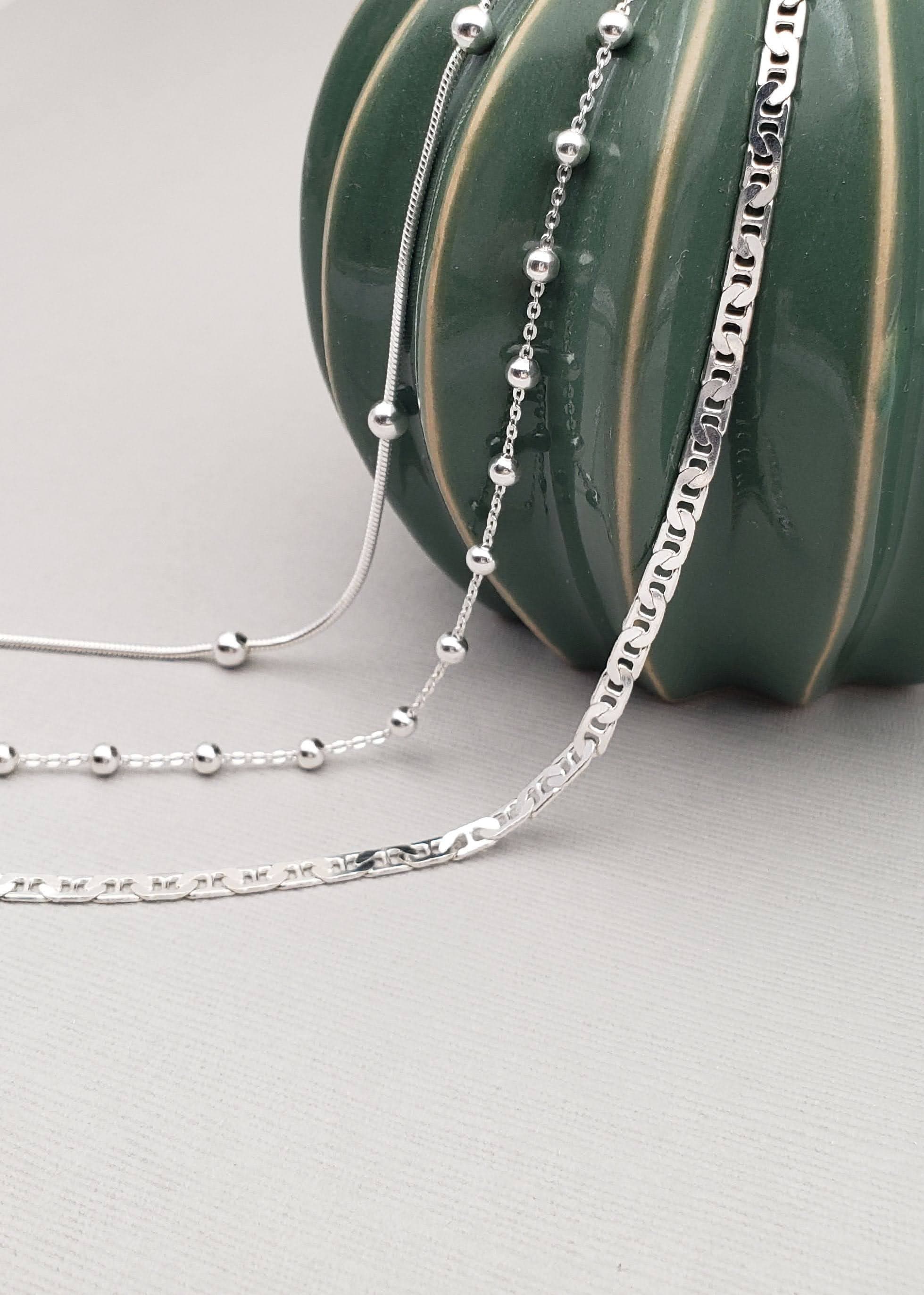 Three anklets artfully draped on a green ceramic pumpkin